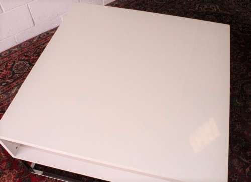A stunning and modern white square coffee table with a magazine/ book shelf on chromed table legs