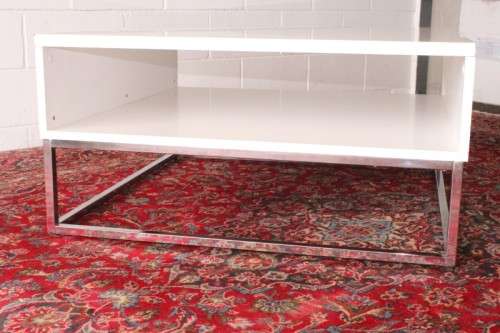 A stunning and modern white square coffee table with a magazine/ book shelf on chromed table legs