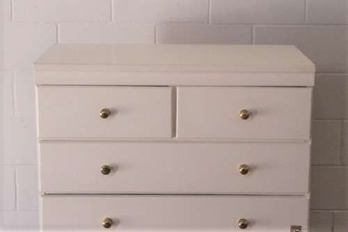 A tall 4-over-2 white painted chest of drawers with brass handles and ample storage space