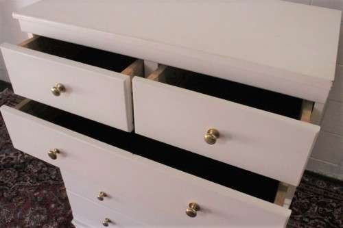 A tall 4-over-2 white painted chest of drawers with brass handles and ample storage space