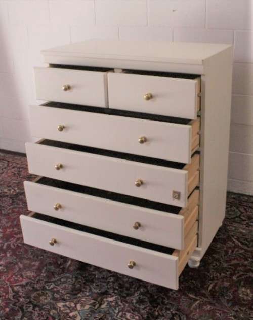 A tall 4-over-2 white painted chest of drawers with brass handles and ample storage space