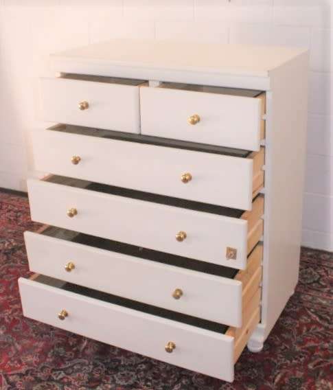 A tall 4-over-2 white painted chest of drawers with brass handles and ample storage space