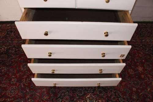 A tall 4-over-2 white painted chest of drawers with brass handles and ample storage space