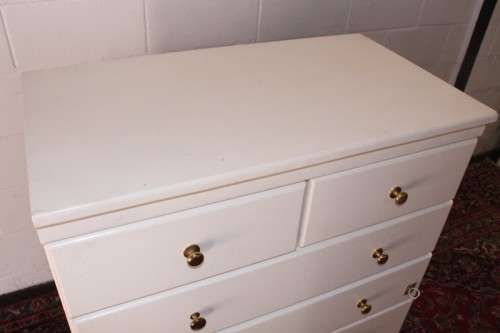 A tall 4-over-2 white painted chest of drawers with brass handles and ample storage space