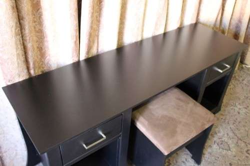 A stunning modern styled black wooden dressing table with two drawers and a suede stool.