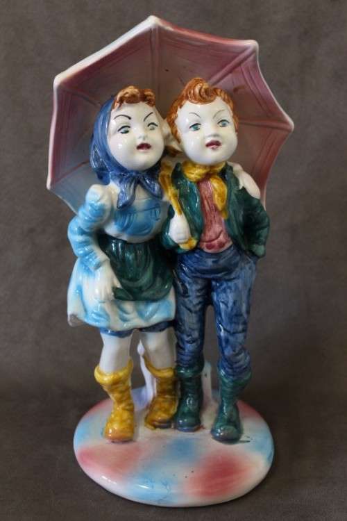 A beautiful porcelain figurine of a young boy and girl under an umbrella, fabulous on display.