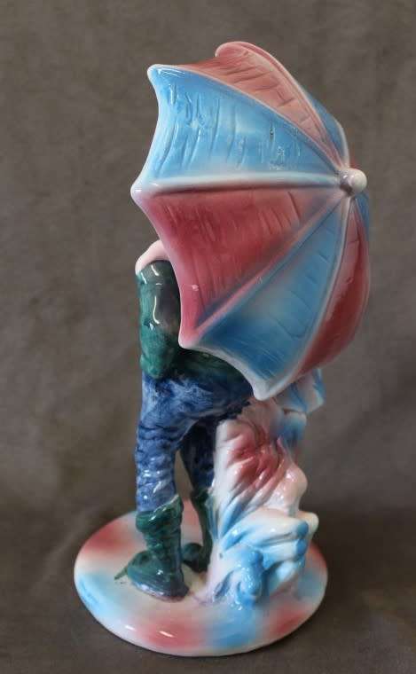 A beautiful porcelain figurine of a young boy and girl under an umbrella, fabulous on display.