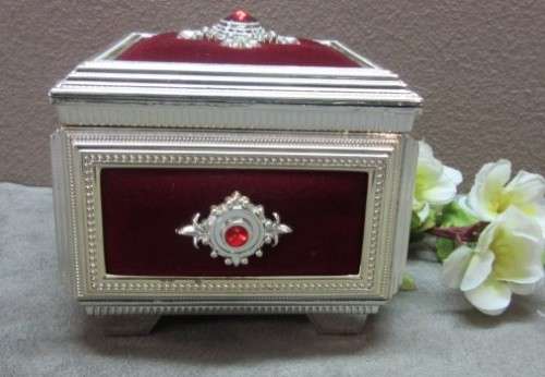 A beautiful silver metal and red velvet covered musical box, stunning on a dresser.