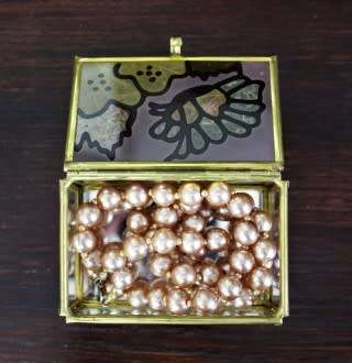 A charming coloured glass trinket box with a gold-coloured frame and mirror base. Lifespace Sale