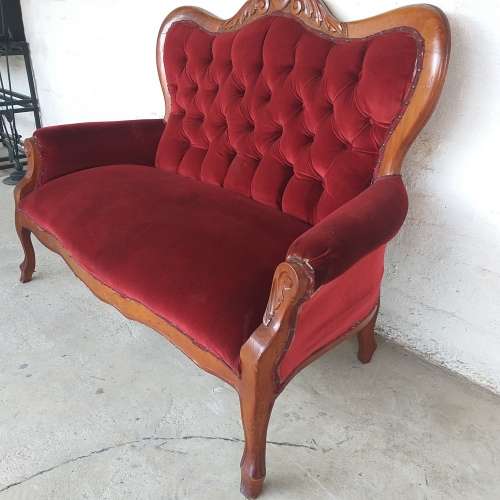 A lovely antique mid-century two-seater carved English Teak red velvet button-back sofa