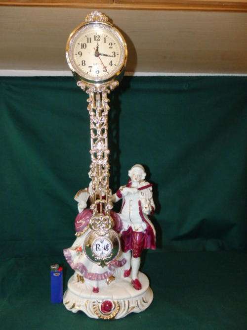 A STUNNING PORCELAIN STATUE WITH A QUARTZ PENDULUM CLOCK IN EXCELLENT CONDITION