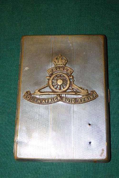 AN AMAZING VINTAGE (1922 TO 1953) SILVER PLATED CIGARETTE CASE WITH A SA ARTILLERY KINGS CROWN BADGE