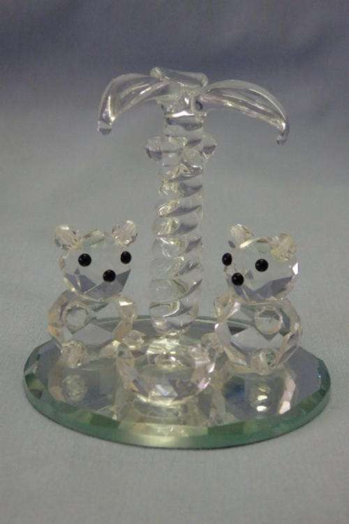 A BEAUTIFUL CRYSTAL ORNAMENT CONSISTING OF TWO HANDMADE CRYSTAL BEARS LOUNGING UNDER A PALMTREE