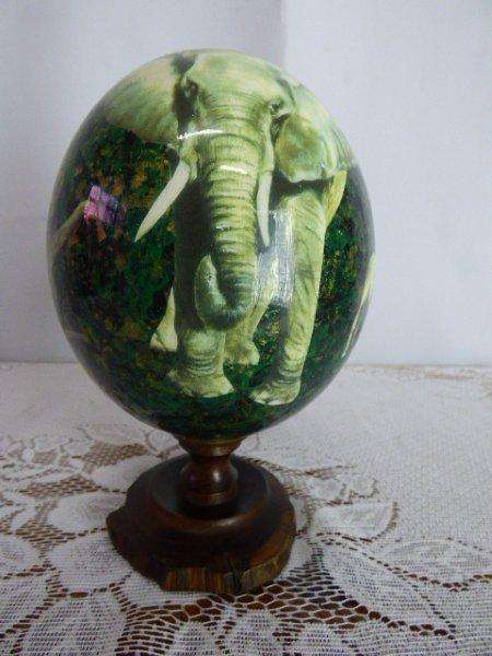 AN EXQUISITE OSTRICH SHAPED EGG DEPICTING SOUTH AFRICAS BIG FIVE, GLAZED ON A WOOD STAND. STUNNING!!