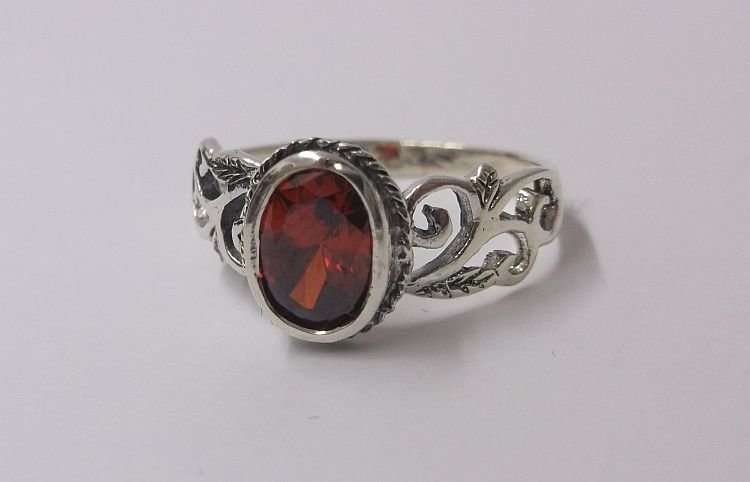 AN EYE CATCHING SOLID STERLING SILVER RING SET WITH A FIERY RED FACETED STONE ..,.TE PRAGTIG !!!