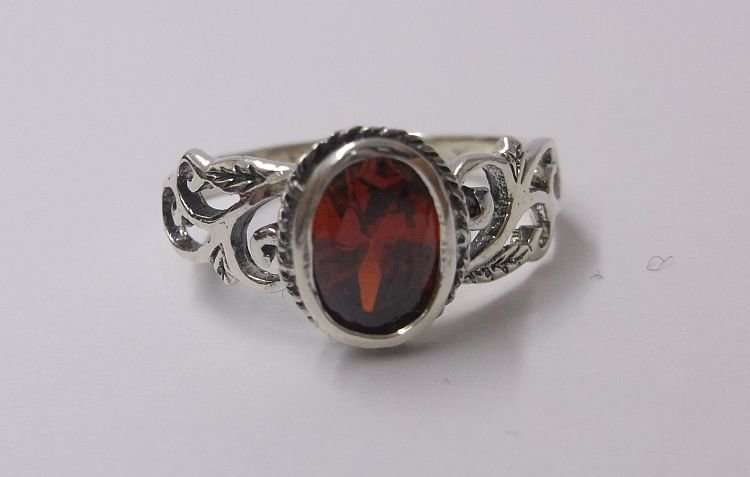 AN EYE CATCHING SOLID STERLING SILVER RING SET WITH A FIERY RED FACETED STONE ..,.TE PRAGTIG !!!