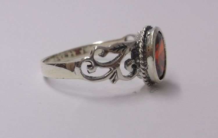 AN EYE CATCHING SOLID STERLING SILVER RING SET WITH A FIERY RED FACETED STONE ..,.TE PRAGTIG !!!