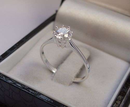 A PETITE STERLING SILVER RING SET WITH A SINGLE FACETED CZ STONE - SIZE N AND A HALF