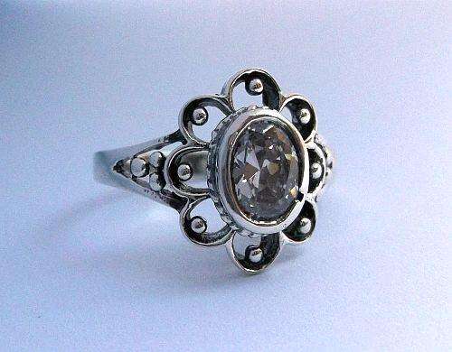 A DAZZLING STERLING SILVER RING SET WITH A FACETED CLEAR STONE .....