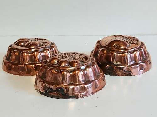 THREE VINTAGE COPPER JELLY MOULDS WITH A FRUIT MOTIF
