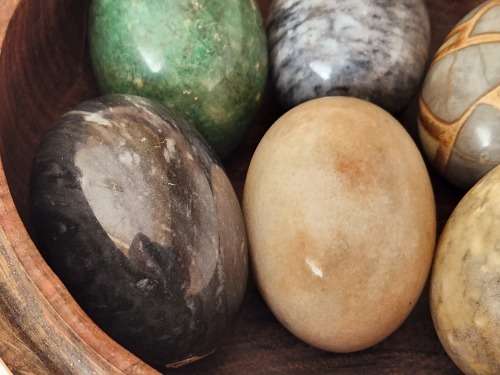 6 HIGHLY POLISHED LARGE SEMI-PRECIOUS GEMSTONE EGGS IN A CARVED WOODEN BOWL