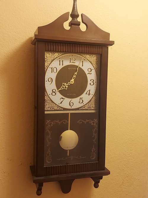 VINTAGE RHYTHM BATTERY STRIKE WALL CLOCK IN A WOODEN CASING WITH A PENDULUM, NOT TESTED