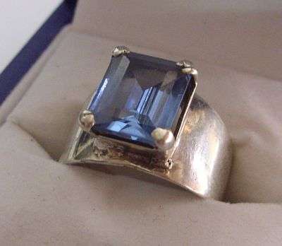 A WIDE WEIGHTY STERLING SILVER RING SET WITH A BEAUTIFUL FACETED BLUE STONE