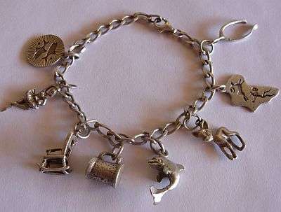 A WEIGHTY STERLING SILVER CHARM BRACELET WITH 8 CHARMS