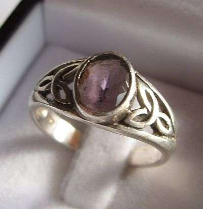 A STERLING SILVER RING WITH CELTIC DESIGN AND FACETED AMETHYST