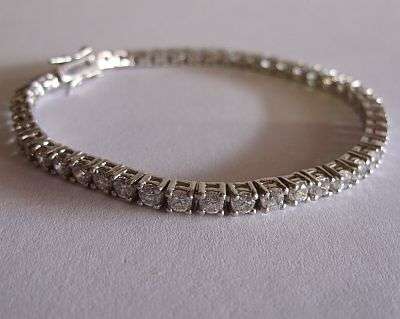 A BEAUTIFUL STERLING SILVER TENNIS BRACELET WITH MANY FACETED CZ STONES