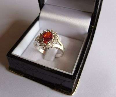 AN EYE CATCHING STERLING SILVER RING WITH A FACETED ORANGE STONE AND FACETED CZ STONES
