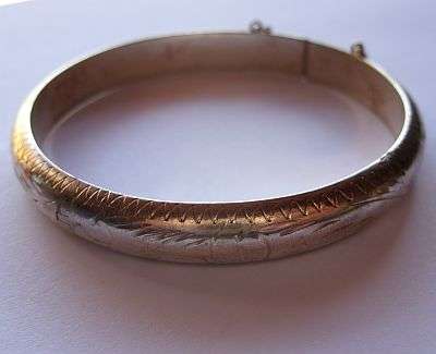 A VINTAGE STERLING SILVER BANGLE WITH SAFETY CHAIN