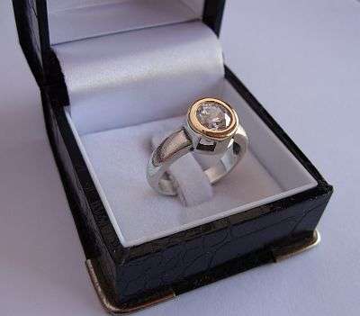 A RAVESHING STERLING SILVER RING SET WITH A WONDERFULLY FACETED CZ - 14 CT "GOLD" RIM