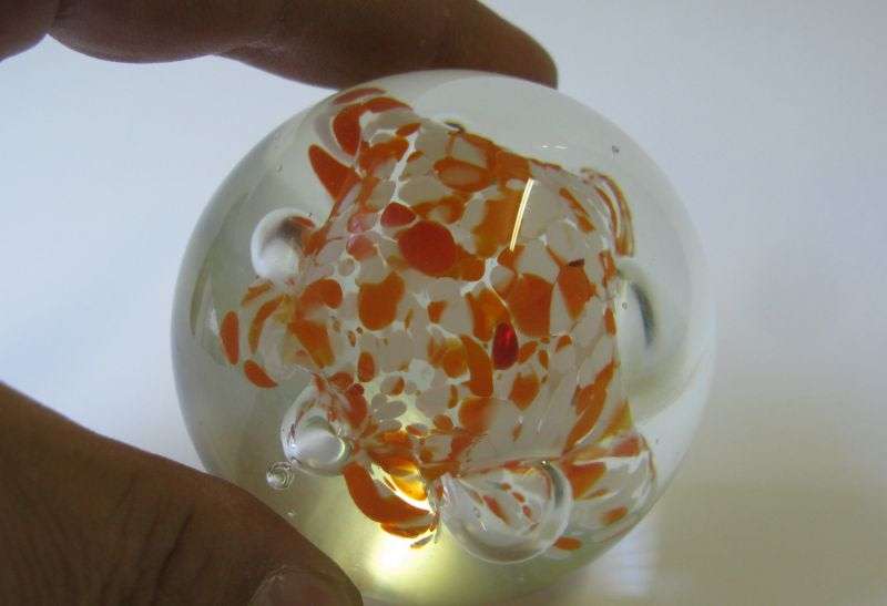 A COOL LOOKING VINTAGE SOLID GLASS PAPERWEIGHT WITH WHITE AND ORANGE SPECKLES DETAIL...NICE !!