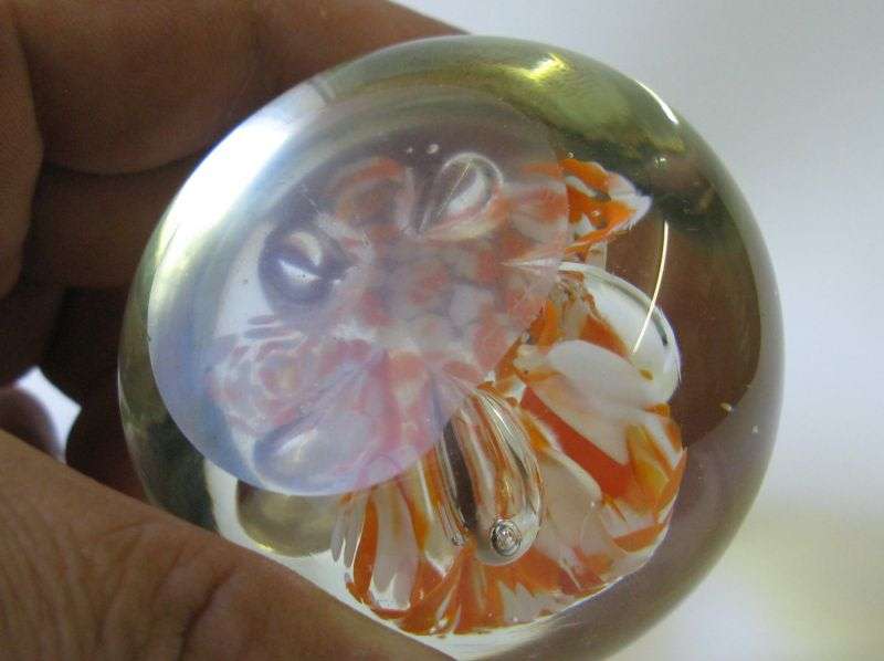 A COOL LOOKING VINTAGE SOLID GLASS PAPERWEIGHT WITH WHITE AND ORANGE SPECKLES DETAIL...NICE !!