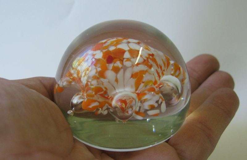 A COOL LOOKING VINTAGE SOLID GLASS PAPERWEIGHT WITH WHITE AND ORANGE SPECKLES DETAIL...NICE !!