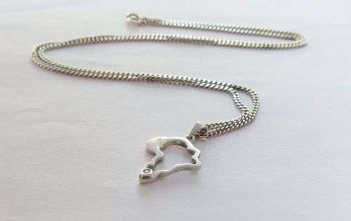 A COOL SOLID STERLING SILVER AFRICA PENDANT SET WITH A FACETED STONE PLUS A STERLING SILVER NECKLACE