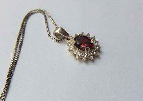 A CHARMING SOLID STERLING SILVER PENDANT SET WITH A FACETED RED STONE PLUS STERLING SILVER NECKLACE