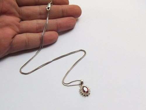 A CHARMING SOLID STERLING SILVER PENDANT SET WITH A FACETED RED STONE PLUS STERLING SILVER NECKLACE