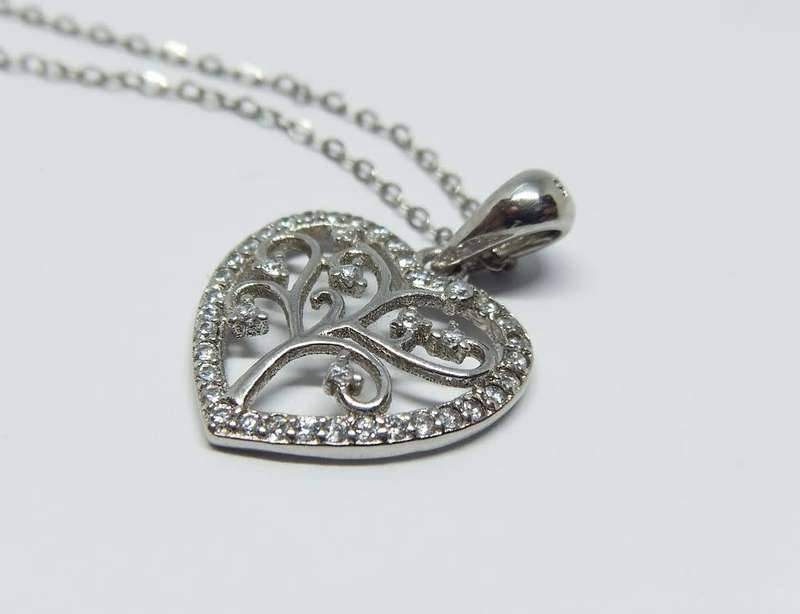 A genuine sterling silver necklace and heart pendant containing the tree of life with clear insets
