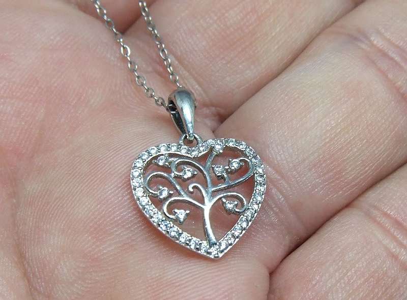 A genuine sterling silver necklace and heart pendant containing the tree of life with clear insets