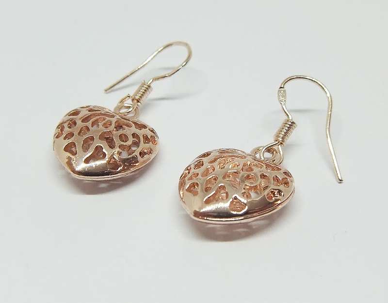 An eye catching unused pair of rose gold plated genuine sterling silver dangling heart earrings