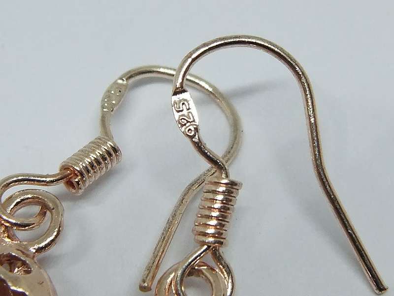 An eye catching unused pair of rose gold plated genuine sterling silver dangling heart earrings