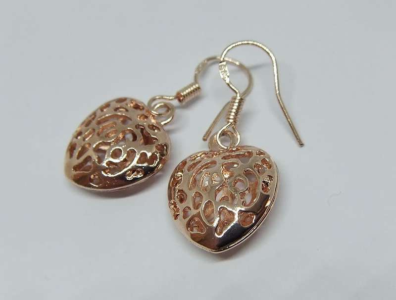 An eye catching unused pair of rose gold plated genuine sterling silver dangling heart earrings