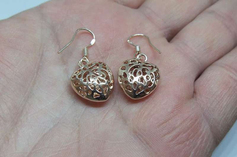 An eye catching unused pair of rose gold plated genuine sterling silver dangling heart earrings