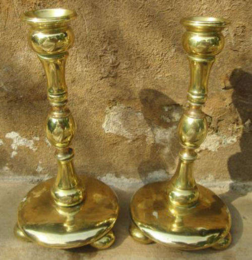 A PAIR OF VINTAGE, SOLID TURNED BRASS CANDLESTICKS RESTING ON BUN FEET.