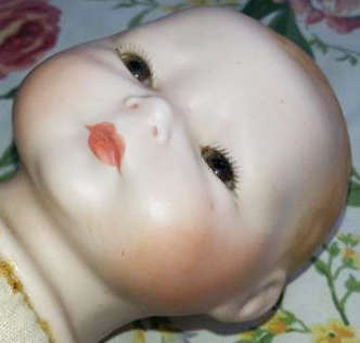 BABY DOLL WITH A PORCELAIN HEAD AND HANDS, A CLOTH BODY THAT NEEDS A GENTLE WASH, NO DAMAGE TO PORCE