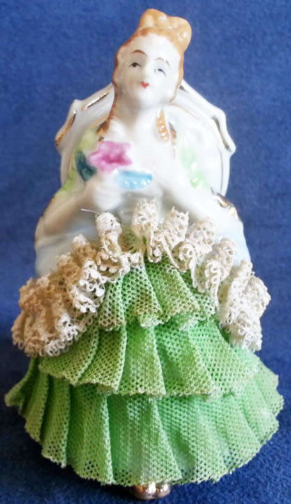 VINTAGE LACE AND PORCELAIN FIGURINE SITTING ON A CHAIR.