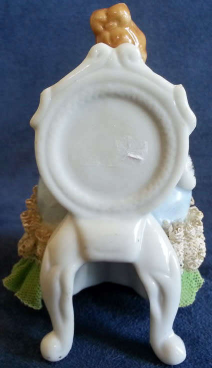 VINTAGE LACE AND PORCELAIN FIGURINE SITTING ON A CHAIR.