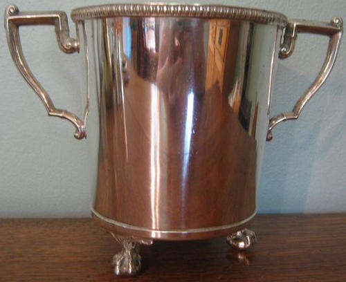 HEAVY QUALITY, E.P.N.S.BOTTLE HOLDER, HAS DECORATIVE HANDLES AND STANDS ON 3 FEET